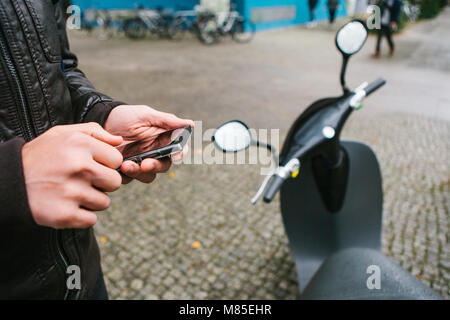 Den Touristen wird die elektrische Scooter durch die mobile Anwendung auf dem Telefon verwenden und distal zu aktivieren. Ein beliebtes Fahrzeug in Berlin und Stockfoto