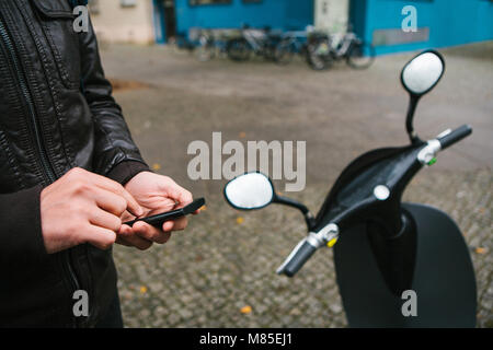 Den Touristen wird die elektrische Scooter durch die mobile Anwendung auf dem Telefon verwenden und distal zu aktivieren. Ein beliebtes Fahrzeug in Berlin und Stockfoto