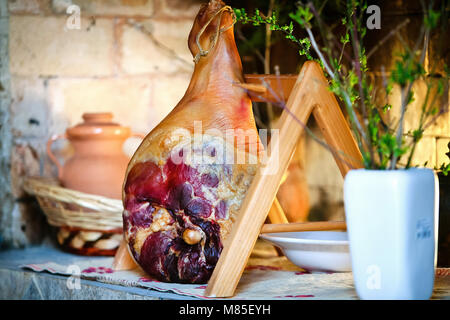 Ganze Schinken auf einem Holzständer. Mediterranen Hintergrund. Traditionelle getrocknetes Fleisch in Dalmatien, Kroatien. Stockfoto