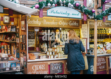 Prag, Dezember 15, 2016: Der Verkäufer bietet dem Käufer eine große Auswahl an Honig und verschiedene Weine. Weihnachtsmarkt. Der Käufer ist zufrieden mit dem purc Stockfoto