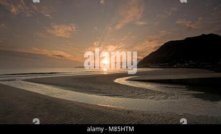 Sonnenaufgang über Llanfairfechan Strand bei Ebbe an der Küste von Nordwales Stockfoto