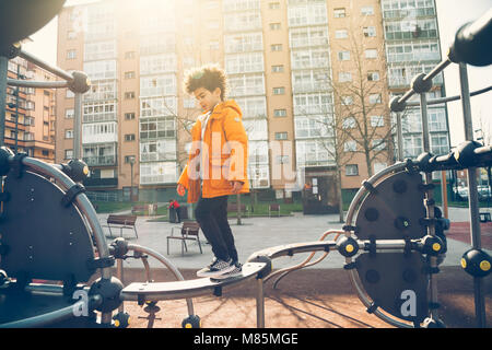 Cute little boy gehen die Balance bar in einem städtischen Spielplatz an einem sonnigen Tag Stockfoto