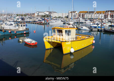 Fischerboote und Yachten im Hafen von Weymouth Dorset mit einem sehr markanten gelben Boot im Vordergrund. Stockfoto
