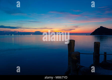 Sonnenuntergang auf dem Meer, mit Blick auf Koh Nang Yuan von Ko Tao, holzstäbchen eines Piers im Vordergrund, und ein rosa orange gelb und blauer Himmel Stockfoto