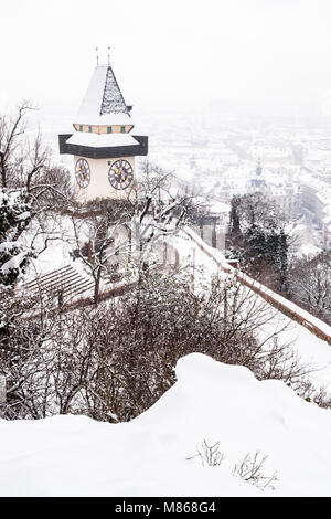 Schnee bedeckt Uhrturm Uhrturm Wahrzeichen auf Berg Schlossberg mit Luftaufnahme der Stadt Graz im Winter Stockfoto