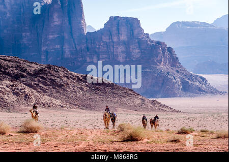 Bédouins mit kamelen vor der beeindruckenden Blue Mountain Ridge in Wadi Rum, Jordanien. Stockfoto