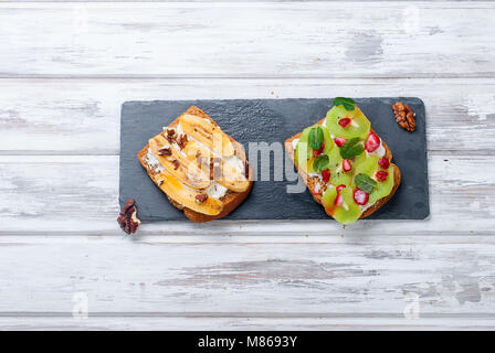 Gesundes Frühstück mit Toast. Süße Brötchen mit Frischkäse und frischen Beeren und Obst auf weißem Hintergrund. Gesunde Ernährung und Diät Konzept. Zu Stockfoto