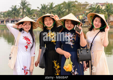 Vier junge Damen, die traditionelle vietnamesische Bambus konischen Hüte in Hoi An, Vietnam Stockfoto