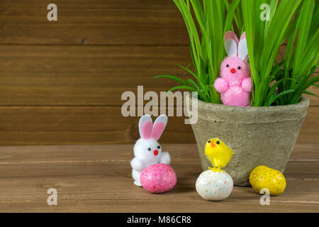 Osterhase und gelben Küken mit Blumentopf und Candy Eier auf rustikalem Holz Stockfoto