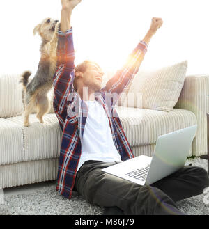 Happy Guy frohlockt mit seinem Hund sitzt in der Nähe der Couch im Livin Stockfoto