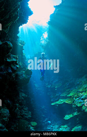 Männliche Scuba Diver posiert in einer Unterwasserwelt Höhle mit lightbeams und Korallen. Stockfoto