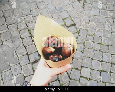 Woman's Hand, die gebratenen Kastanien in Papier gewickelt Stockfoto