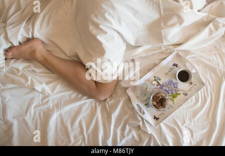 Frühstück Fach neben einer Frau im Bett Stockfoto