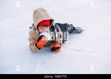 Junge lag auf einem zugefrorenen See mit Schlittschuhen Eis essen Stockfoto