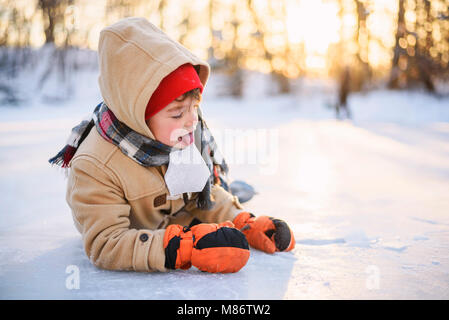 Junge lag auf einem zugefrorenen See ein Stück Eis lecken Stockfoto