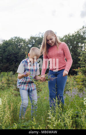 Mädchen und ein Junge Blumen pflücken auf einer Wiese Stockfoto