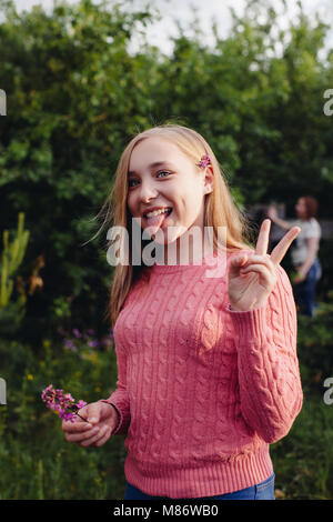 Mädchen ihre Zunge heraus und ein v-Zeichen Stockfoto