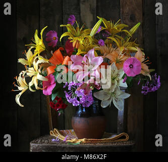 Noch immer leben mit einem Blumenstrauß aus Lilien und anderen Garten Blumen auf einem dunklen Hintergrund. Stockfoto