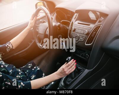 Junge Frau Zahnräder ändern in dem Auto. Ein Auto fahren. Manuelle Übertragung. Moderne Innenraum Stockfoto