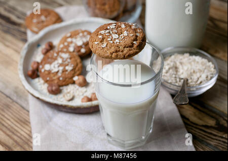 Oat hausgemachte Kekse und Milch in ein Glas und eine Flasche auf einem Holztisch Stockfoto