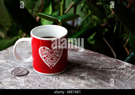 Rot Tasse mit Herz auf einem Holztisch Stockfoto
