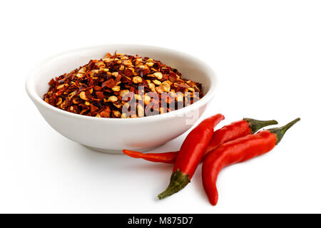 Grob Gemahlenes Chili peppers aus weisser Keramik Schüssel isoliert auf Weiss. Frische Chilis. Stockfoto