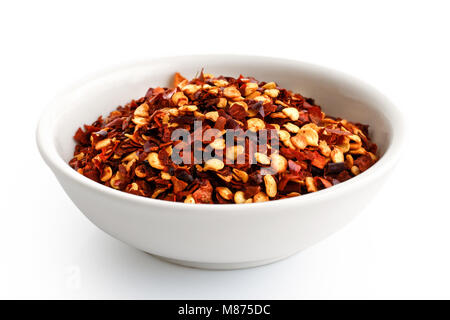 Grob Gemahlenes Chili peppers aus weisser Keramik Schüssel isoliert auf Weiss. Stockfoto