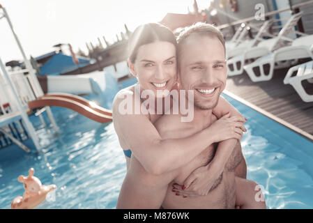 Junge Frau und Mann umarmen im Pool begeistert Stockfoto