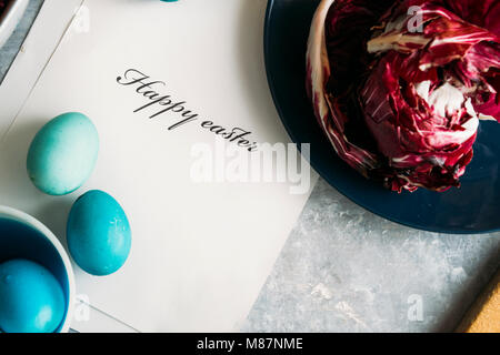 Natürliche Ostereier färben mit rohen Zutaten, Ansicht von oben in Pastell-blaue Ostereier aus Rotkohl auf grauem Hintergrund mit Tabelle Stockfoto