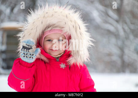 Kleine süße Mädchen in einer großen Fell Kapuze ihre Hand winken Stockfoto