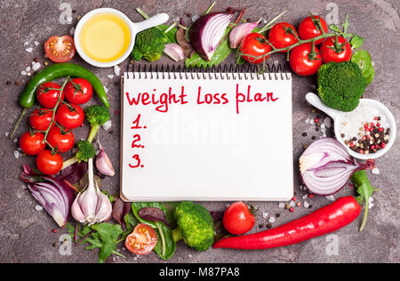 Frisches Bio-Gemüse, Kräutern und Gewürzen. Gemischter Salat, Tomaten, Chili, Knoblauch und Öffnen leer Notebook mit Plan essen. Gewicht-verlust-Konzept. Produkt Stockfoto