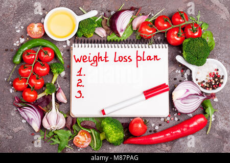 Frisches Bio-Gemüse, Kräutern und Gewürzen. Gemischter Salat, Tomaten, Chili, Knoblauch und Öffnen leer Notebook mit Plan essen. Gewicht-verlust-Konzept. Produkt Stockfoto