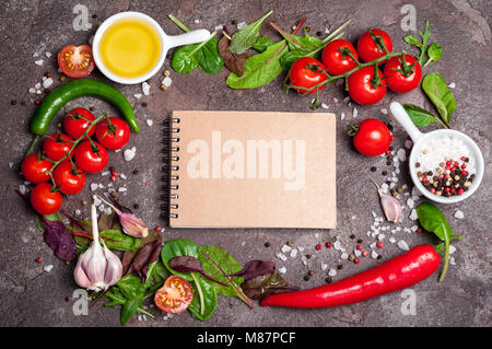 Frisches Bio-Gemüse, Olivenöl, Kräuter, Gewürze und Notebook auf dunklem Hintergrund. Gesunde Ernährung, gesunde Lebensweise und Ernährung Konzept. Kochen Salat. Stockfoto