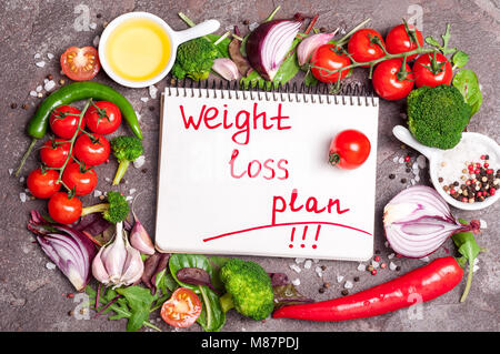 Frisches Bio-Gemüse, Kräutern und Gewürzen. Gemischter Salat, Tomaten, Chili, Knoblauch und Öffnen leer Notebook mit Plan essen. Gewicht-verlust-Konzept. Produkt Stockfoto