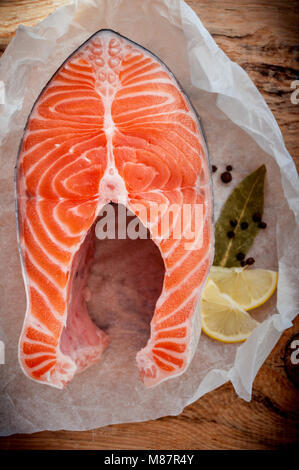 Roher Lachs Fisch Steak mit Zitrone und Gewürzen auf Holz- rustikalen Hintergrund. Frischen Fisch. Ansicht von oben Stockfoto