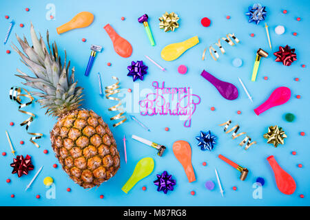 Happy birthday Hintergrund. Festliche Ananas, Kerzen, Konfetti, Luftballons, Luftschlangen und Dekoration auf blauem Hintergrund. Bunte Feier bac Stockfoto