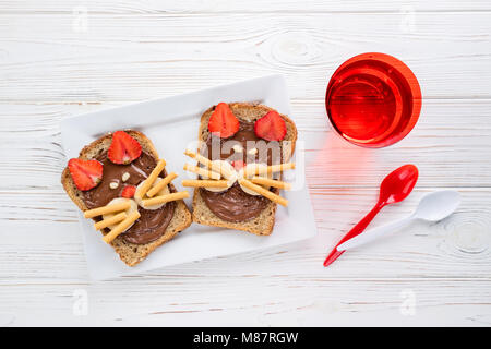 Sandwiches und Milch für die Kinder. Lustige Katzen Gesicht Sandwiches mit Beeren, Schokolade, Bananen, Nüsse. Ansicht von oben Stockfoto