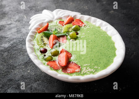 Smoothie Schüssel mit Obst, Beeren, Schokolade und Sesam auf dunklen konkreten Hintergrund. Grüne Smoothie zum Frühstück. Super Food Konzept Stockfoto