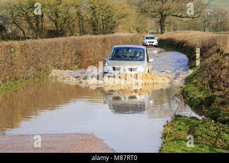 Auto durch überflutete Straße fahren in der Nähe des Flusses Axe in East Devon Stockfoto