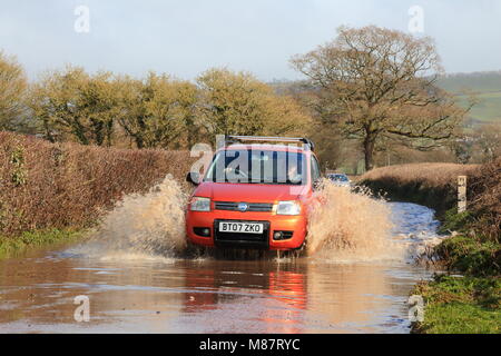 Auto durch überflutete Straße fahren in der Nähe des Flusses Axe in East Devon Stockfoto