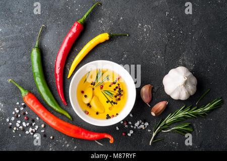 Kräuter und Gewürze. Rosmarin, Chili, Knoblauch, Olivenöl, Salz und Pfeffer auf dunklen Tabelle Stockfoto