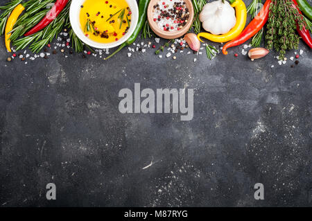 Kräuter und Gewürze. Rosmarin, Thymian, Chili, Knoblauch, Olivenöl, Salz und Pfeffer auf dunklen Tisch. Zutaten zum Kochen. Ansicht von oben und kopieren Sie Raum für Ihre reci Stockfoto