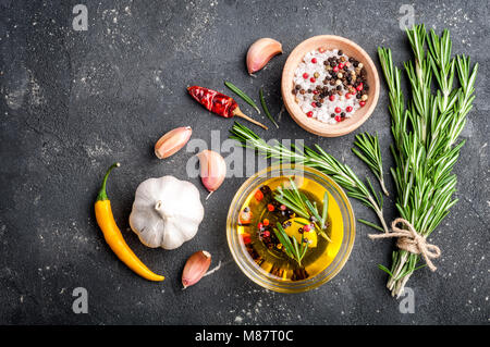 Kräuter und Gewürze. Rosmarin, Chili, Knoblauch, Olivenöl, Salz und Pfeffer auf dunklen Tisch. Zutaten zum Kochen. Ansicht von oben und kopieren Sie Raum für Ihre reci Stockfoto