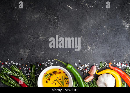 Kräuter und Gewürze. Rosmarin, Chili, Knoblauch, Olivenöl, Salz und Pfeffer auf dunklen Tisch. Zutaten zum Kochen. Ansicht von oben und kopieren Sie Raum für Ihr Rezept Stockfoto