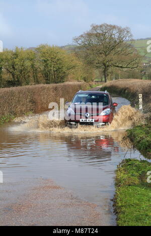 Auto durch überflutete Straße fahren in der Nähe des Flusses Axe in East Devon Stockfoto