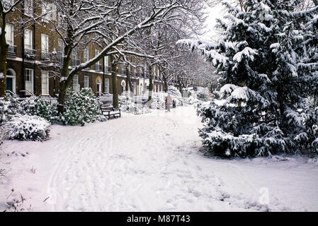 Öffentlichen Parkbank viktorianischen Häusern, hinter bedeckt mit Schnee London winter Stockfoto