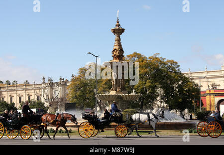 Touristen im Pferdewagen, vorbei an den Brunnen der Vier Jahreszeiten in Sevilla Stockfoto