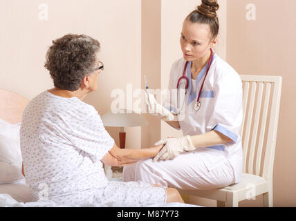 Medical Assistant überprüft die Adern der älteren Frau, die für Transfusionen Stockfoto
