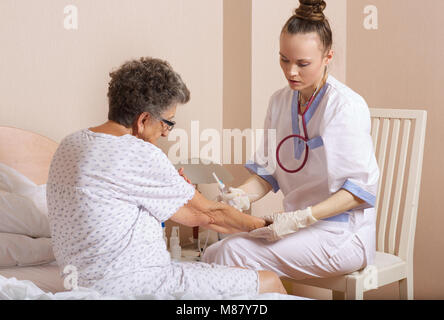 Medical Assistant überprüft die Adern der älteren Frau, die für Transfusionen Stockfoto