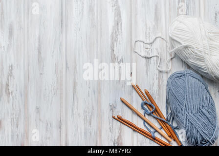 Weiße und graue stricken Threads und Haken für das Stricken auf weißen alten Holztisch, selektiver Fokus. Kopieren Sie Raum, Ansicht von oben Stockfoto